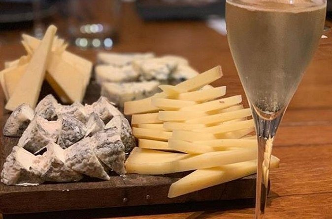 A cheese board beside a filled champagne flute