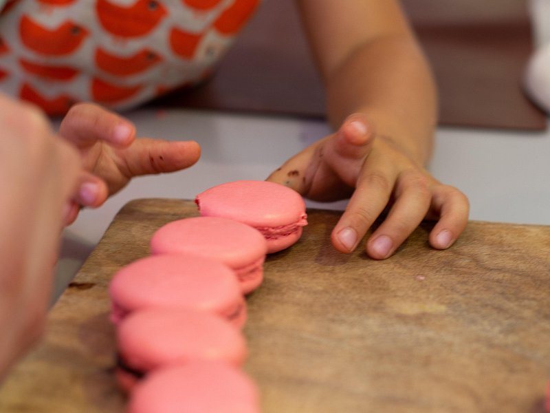 Pink macarons being set out in a row on a pastry counter