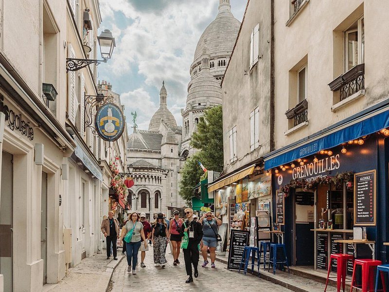 A Montmartre street climbing towards the white domes of the Sacre-Coeur