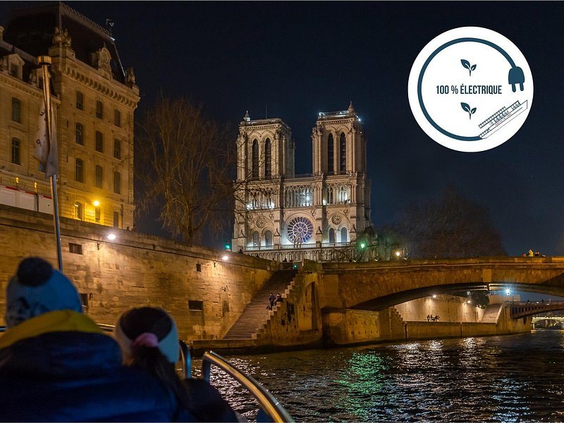 Notre-Dame lit at night from the Seine, seen from a passing boat