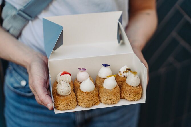 An open patisserie box of choux buns carried out of a Paris shop