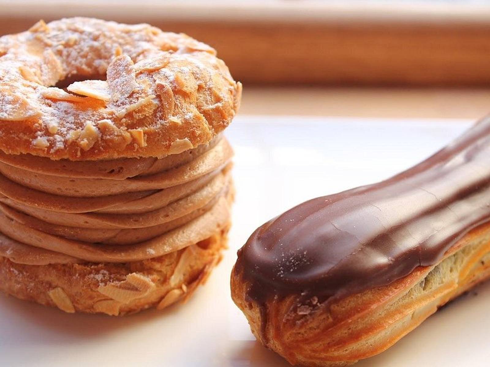 Chocolate-glazed eclairs and choux pastries stacked in a Paris patisserie window